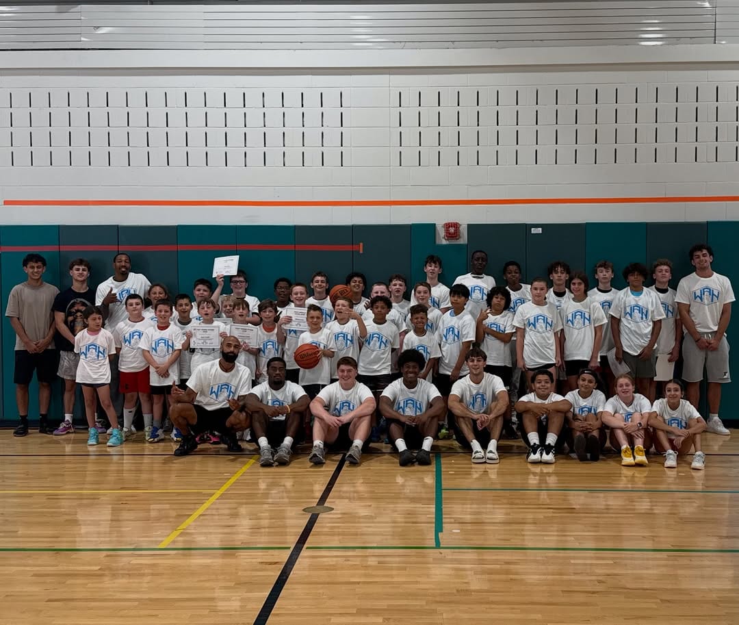 Large group of young players in We All Hoop shirts at a camp